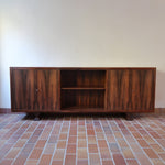 Grande enfilade vintage en palissandre de 240 cm, placage au fil en miroir, deux caissons fermant à clé de part et d'autre d'une niche centrale ouverte, tablettes intérieures en bois clair, reposant sur deux pieds pleins posés en retrait