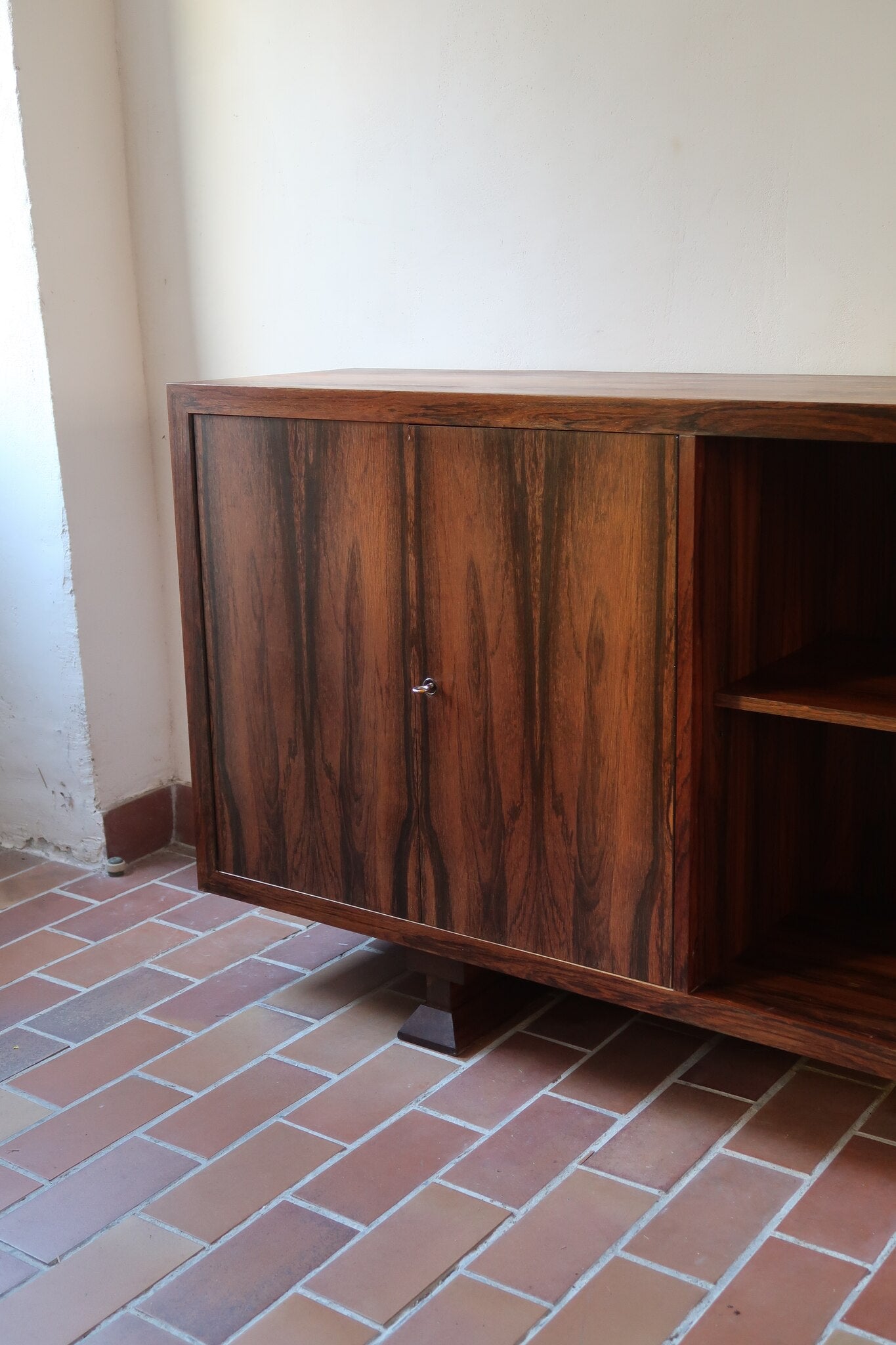 Grande enfilade vintage en palissandre de 240 cm, placage au fil en miroir, deux caissons fermant à clé de part et d'autre d'une niche centrale ouverte, tablettes intérieures en bois clair, reposant sur deux pieds pleins posés en retrait