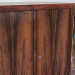 Grande enfilade vintage en palissandre de 240 cm, placage au fil en miroir, deux caissons fermant à clé de part et d'autre d'une niche centrale ouverte, tablettes intérieures en bois clair, reposant sur deux pieds pleins posés en retrait