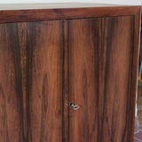 Grande enfilade vintage en palissandre de 240 cm, placage au fil en miroir, deux caissons fermant à clé de part et d'autre d'une niche centrale ouverte, tablettes intérieures en bois clair, reposant sur deux pieds pleins posés en retrait