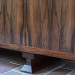 Grande enfilade vintage en palissandre de 240 cm, placage au fil en miroir, deux caissons fermant à clé de part et d'autre d'une niche centrale ouverte, tablettes intérieures en bois clair, reposant sur deux pieds pleins posés en retrait