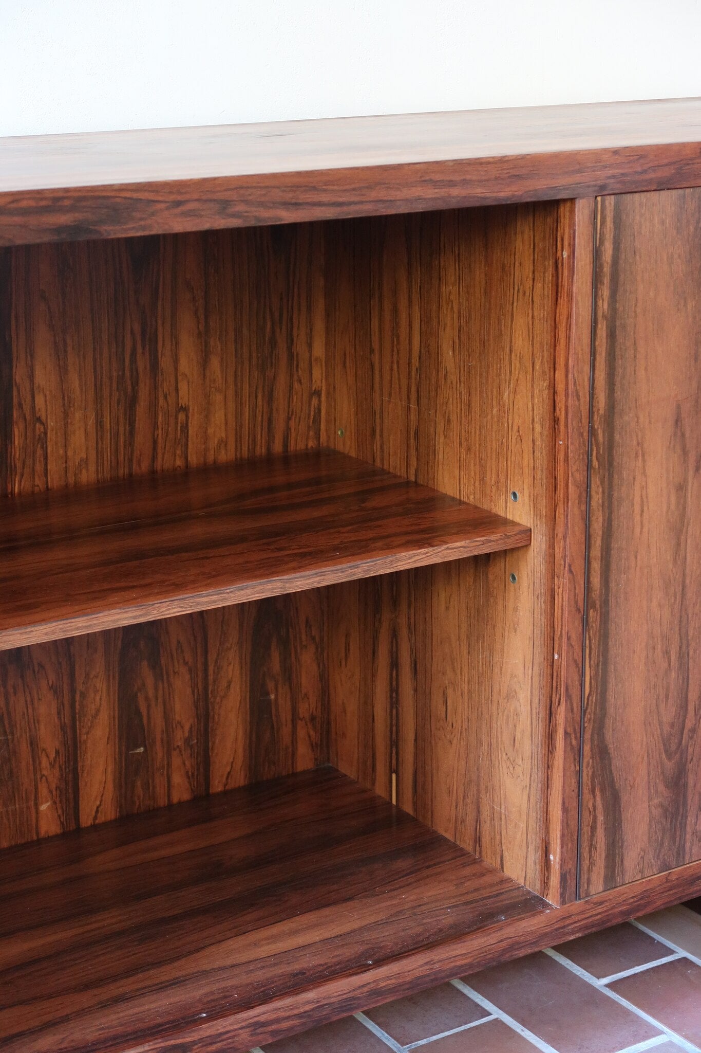 Grande enfilade vintage en palissandre de 240 cm, placage au fil en miroir, deux caissons fermant à clé de part et d'autre d'une niche centrale ouverte, tablettes intérieures en bois clair, reposant sur deux pieds pleins posés en retrait
