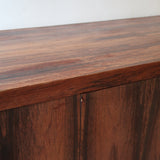 Grande enfilade vintage en palissandre de 240 cm, placage au fil en miroir, deux caissons fermant à clé de part et d'autre d'une niche centrale ouverte, tablettes intérieures en bois clair, reposant sur deux pieds pleins posés en retrait