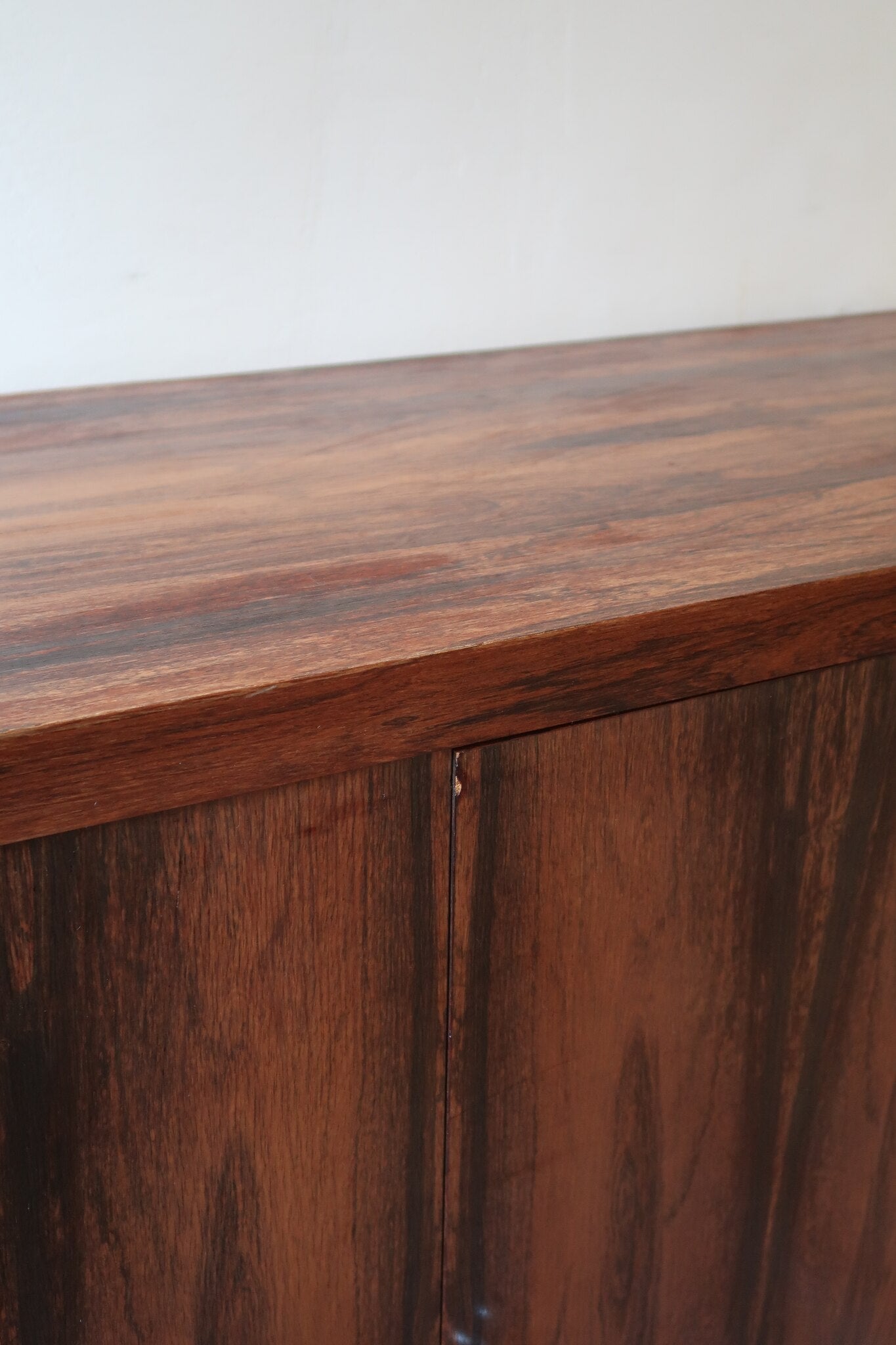 Grande enfilade vintage en palissandre de 240 cm, placage au fil en miroir, deux caissons fermant à clé de part et d'autre d'une niche centrale ouverte, tablettes intérieures en bois clair, reposant sur deux pieds pleins posés en retrait