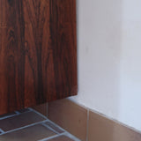 Grande enfilade vintage en palissandre de 240 cm, placage au fil en miroir, deux caissons fermant à clé de part et d'autre d'une niche centrale ouverte, tablettes intérieures en bois clair, reposant sur deux pieds pleins posés en retrait
