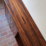 Grande enfilade vintage en palissandre de 240 cm, placage au fil en miroir, deux caissons fermant à clé de part et d'autre d'une niche centrale ouverte, tablettes intérieures en bois clair, reposant sur deux pieds pleins posés en retrait