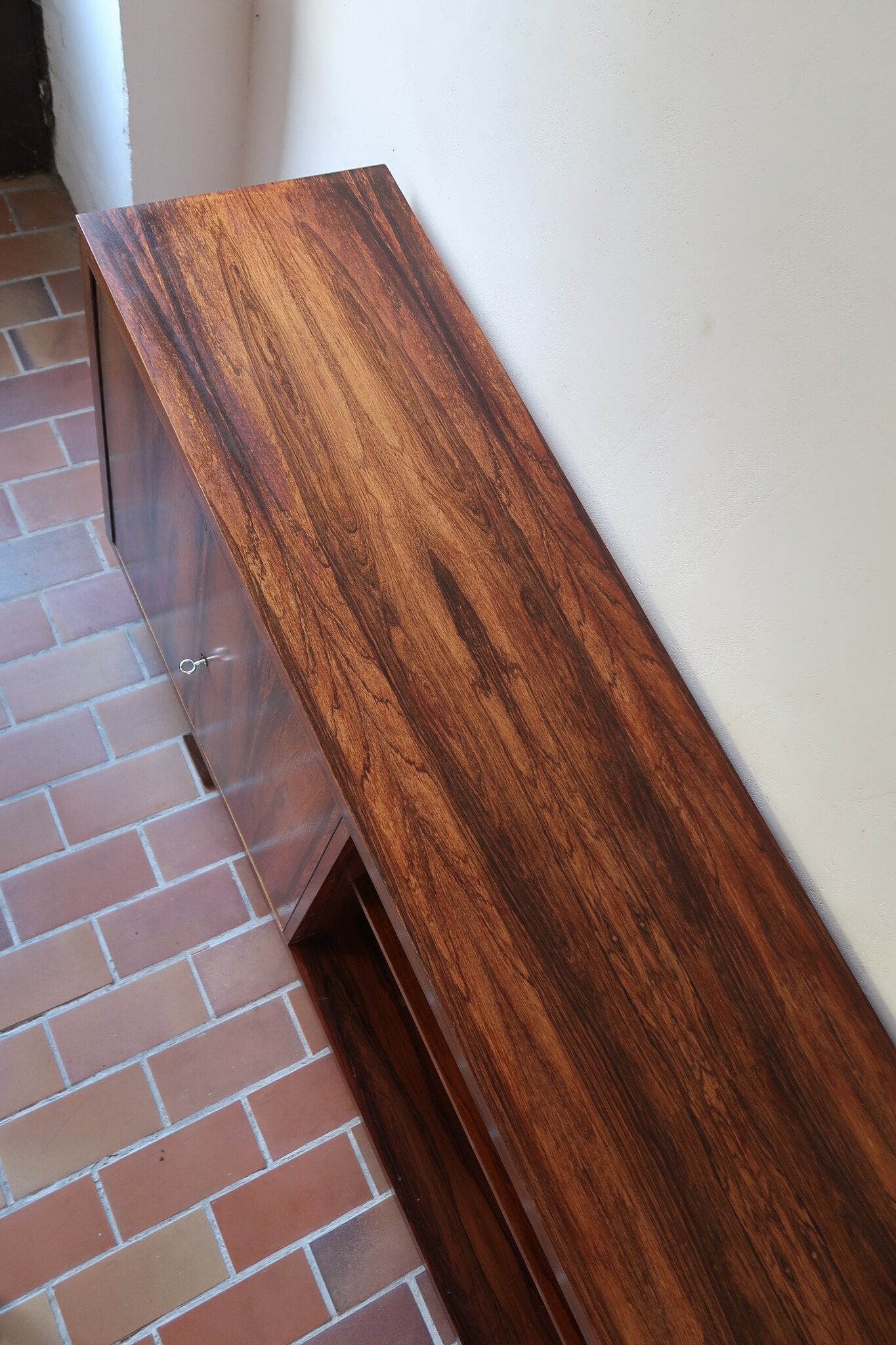 Grande enfilade vintage en palissandre de 240 cm, placage au fil en miroir, deux caissons fermant à clé de part et d'autre d'une niche centrale ouverte, tablettes intérieures en bois clair, reposant sur deux pieds pleins posés en retrait