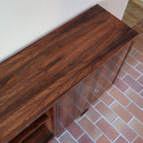 Grande enfilade vintage en palissandre de 240 cm, placage au fil en miroir, deux caissons fermant à clé de part et d'autre d'une niche centrale ouverte, tablettes intérieures en bois clair, reposant sur deux pieds pleins posés en retrait