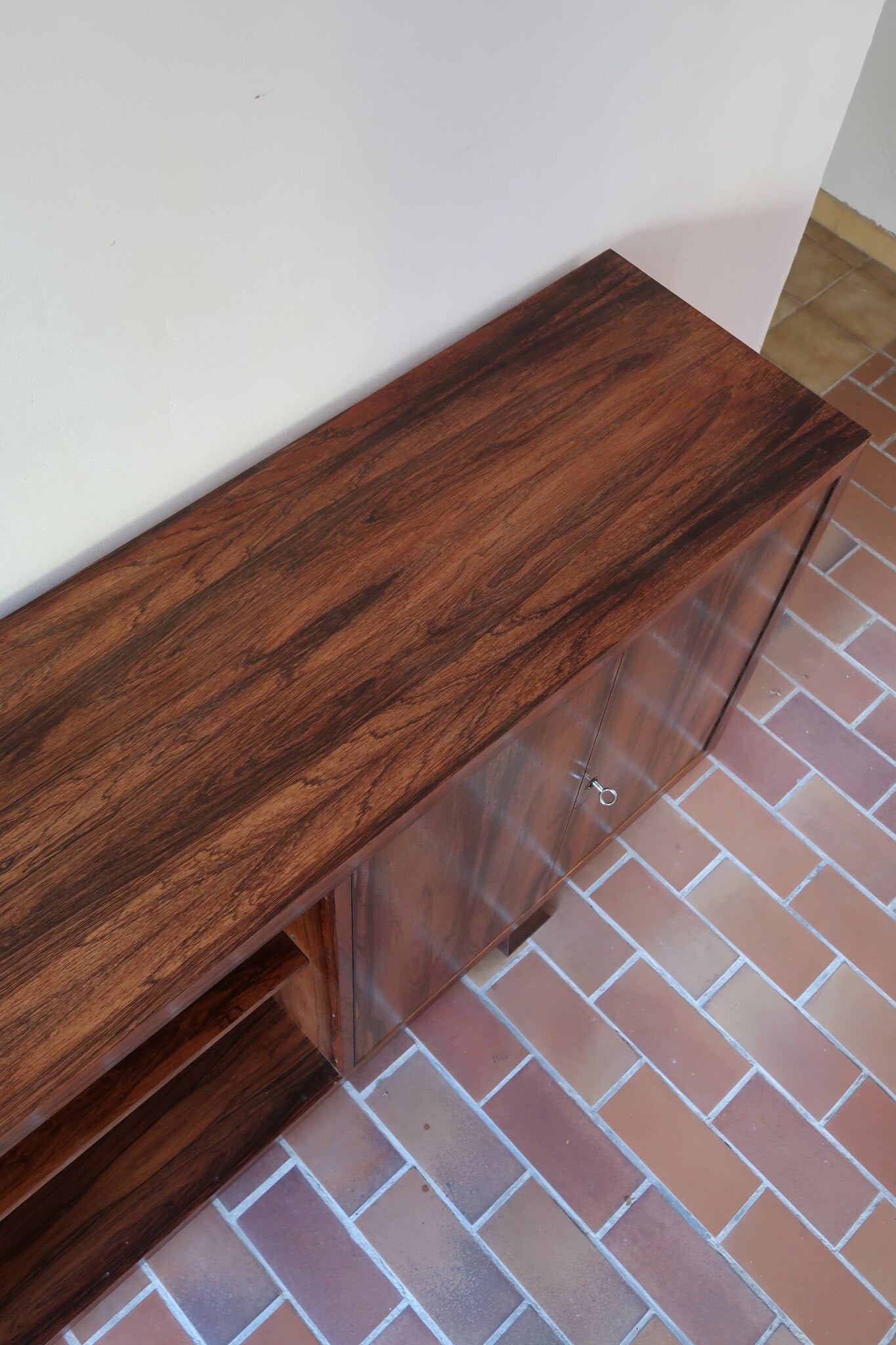 Grande enfilade vintage en palissandre de 240 cm, placage au fil en miroir, deux caissons fermant à clé de part et d'autre d'une niche centrale ouverte, tablettes intérieures en bois clair, reposant sur deux pieds pleins posés en retrait