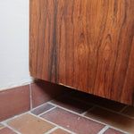 Grande enfilade vintage en palissandre de 240 cm, placage au fil en miroir, deux caissons fermant à clé de part et d'autre d'une niche centrale ouverte, tablettes intérieures en bois clair, reposant sur deux pieds pleins posés en retrait