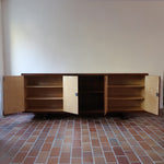 Grande enfilade vintage en palissandre de 240 cm, placage au fil en miroir, deux caissons fermant à clé de part et d'autre d'une niche centrale ouverte, tablettes intérieures en bois clair, reposant sur deux pieds pleins posés en retrait
