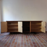 Grande enfilade vintage en palissandre de 240 cm, placage au fil en miroir, deux caissons fermant à clé de part et d'autre d'une niche centrale ouverte, tablettes intérieures en bois clair, reposant sur deux pieds pleins posés en retrait