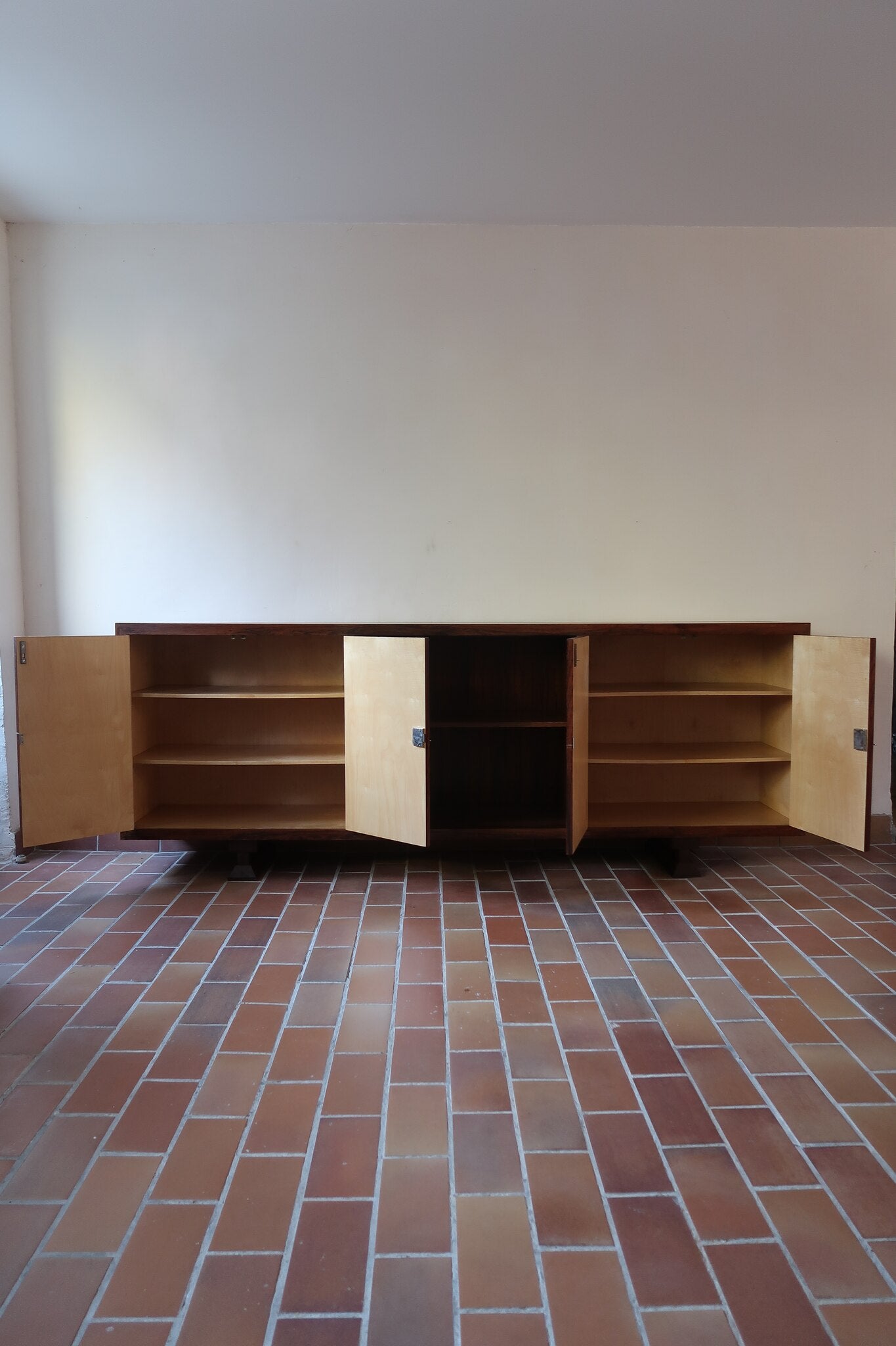 Grande enfilade vintage en palissandre de 240 cm, placage au fil en miroir, deux caissons fermant à clé de part et d'autre d'une niche centrale ouverte, tablettes intérieures en bois clair, reposant sur deux pieds pleins posés en retrait