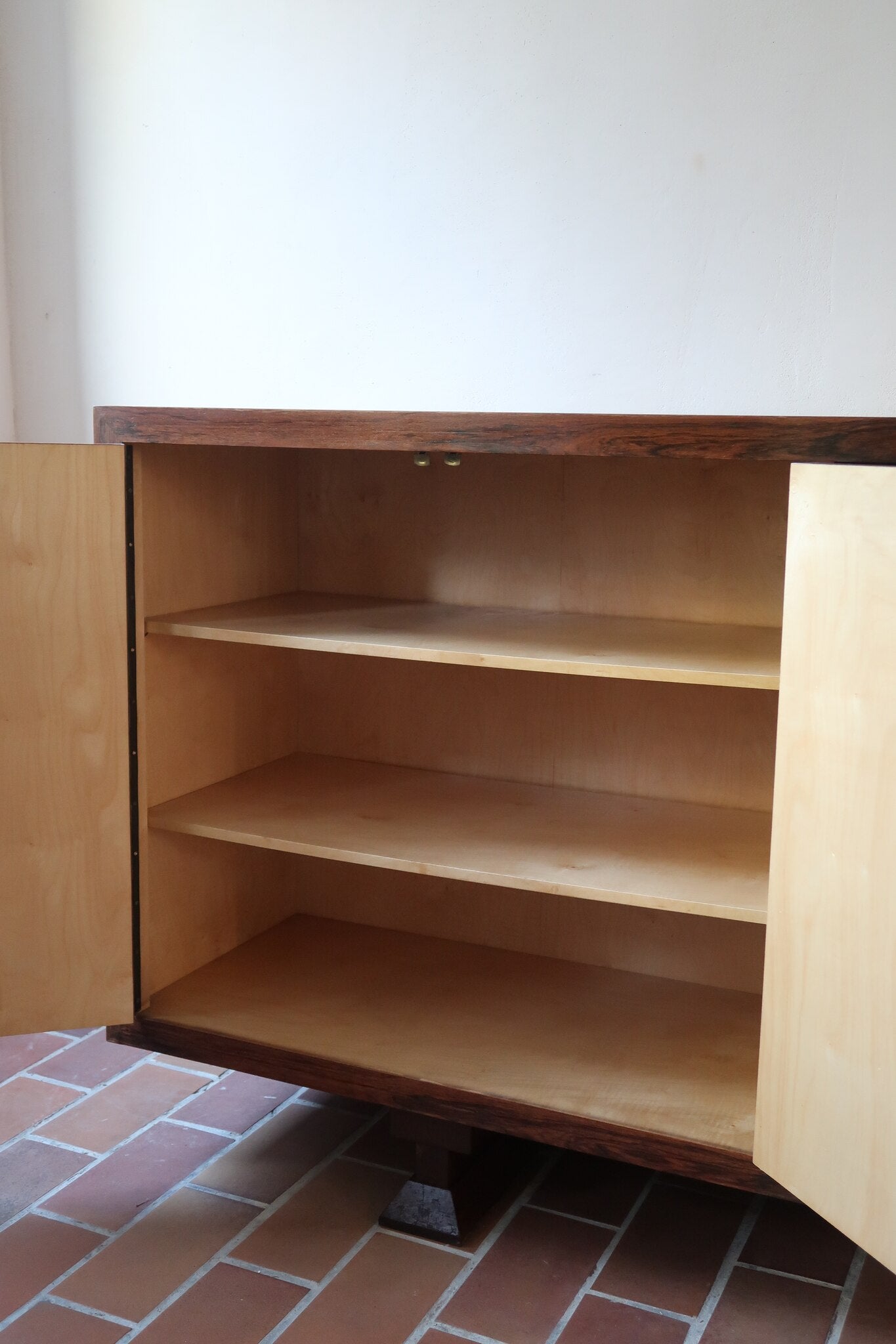 Grande enfilade vintage en palissandre de 240 cm, placage au fil en miroir, deux caissons fermant à clé de part et d'autre d'une niche centrale ouverte, tablettes intérieures en bois clair, reposant sur deux pieds pleins posés en retrait