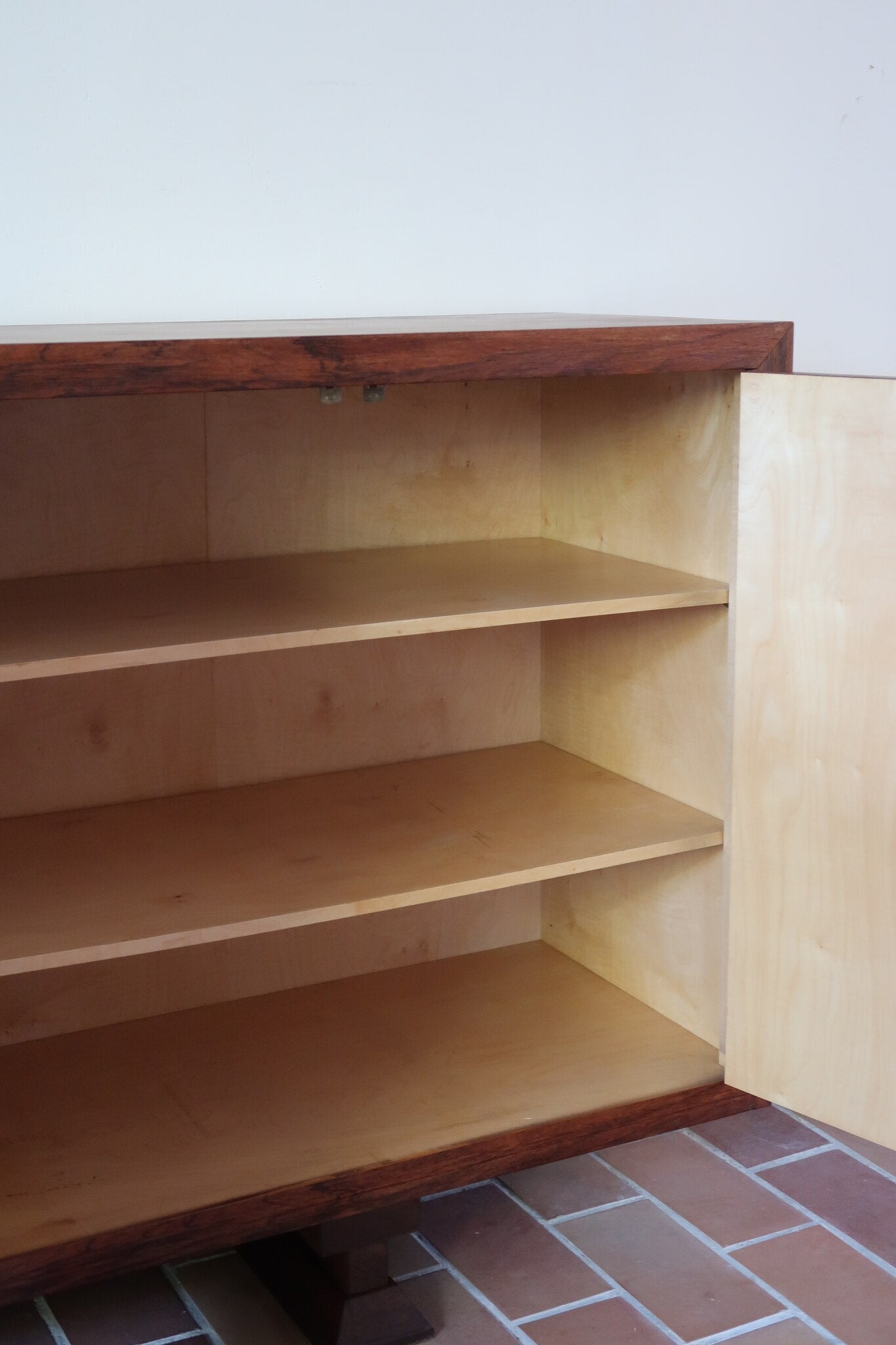Grande enfilade vintage en palissandre de 240 cm, placage au fil en miroir, deux caissons fermant à clé de part et d'autre d'une niche centrale ouverte, tablettes intérieures en bois clair, reposant sur deux pieds pleins posés en retrait