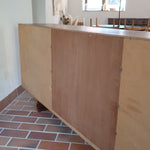 Grande enfilade vintage en palissandre de 240 cm, placage au fil en miroir, deux caissons fermant à clé de part et d'autre d'une niche centrale ouverte, tablettes intérieures en bois clair, reposant sur deux pieds pleins posés en retrait