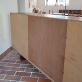 Grande enfilade vintage en palissandre de 240 cm, placage au fil en miroir, deux caissons fermant à clé de part et d'autre d'une niche centrale ouverte, tablettes intérieures en bois clair, reposant sur deux pieds pleins posés en retrait