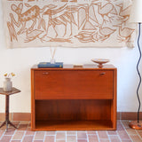 Meuble bar vintage en bois de teck, années 90, abattant sur deux compas chromés découvrant un intérieur doublé de verre noir, poignée sculptée dans la masse, niche basse ouverte sur toute la largeur