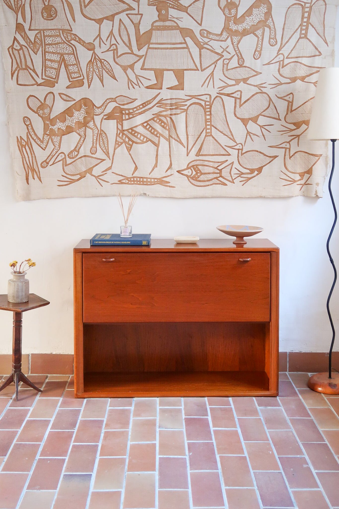 Meuble bar vintage en bois de teck, années 90, abattant sur deux compas chromés découvrant un intérieur doublé de verre noir, poignée sculptée dans la masse, niche basse ouverte sur toute la largeur