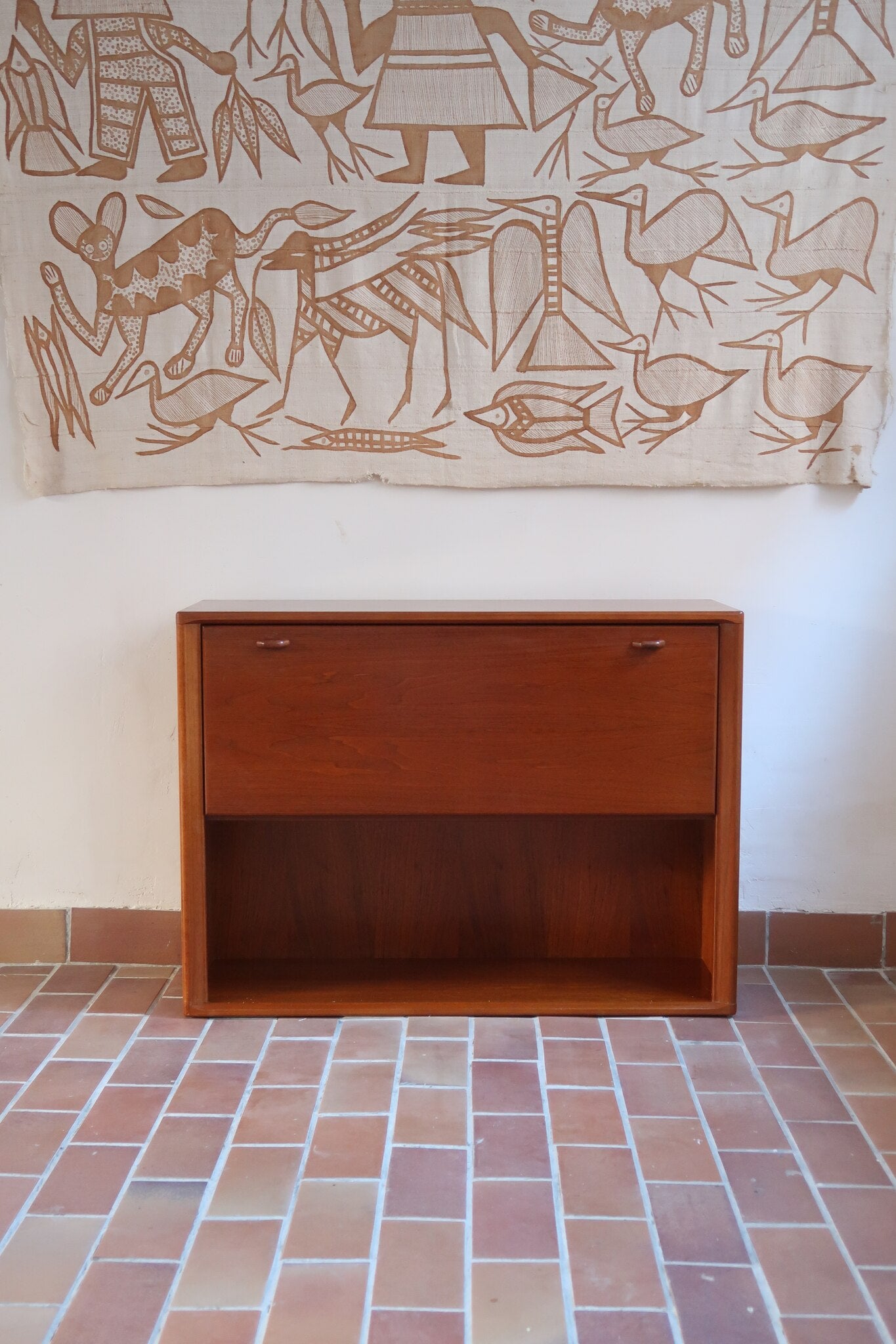 Meuble bar vintage en bois de teck, années 90, abattant sur deux compas chromés découvrant un intérieur doublé de verre noir, poignée sculptée dans la masse, niche basse ouverte sur toute la largeur