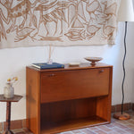 Meuble bar vintage en bois de teck, années 90, abattant sur deux compas chromés découvrant un intérieur doublé de verre noir, poignée sculptée dans la masse, niche basse ouverte sur toute la largeur