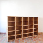 Meuble à casiers vintage en bois clair, style atelier industriel, avec 20 compartiments ouverts pour rangement de livres, vinyles ou objets décoratifs, présenté seul et en mise en situation.