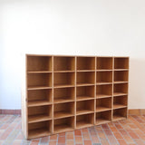 Meuble à casiers vintage en bois clair, style atelier industriel, avec 20 compartiments ouverts pour rangement de livres, vinyles ou objets décoratifs, présenté seul et en mise en situation.