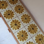 Meuble TV vintage en bois des années 70 avec plateau en céramique à motif floral, trois tiroirs et niches ouvertes.