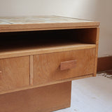 Meuble TV vintage en bois des années 70 avec plateau en céramique à motif floral, trois tiroirs et niches ouvertes.