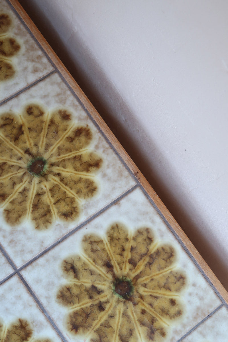Meuble TV vintage en bois des années 70 avec plateau en céramique à motif floral, trois tiroirs et niches ouvertes.