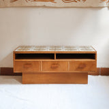 Meuble TV vintage en bois des années 70 avec plateau en céramique à motif floral, trois tiroirs et niches ouvertes.