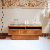 Meuble TV vintage en bois des années 70 avec plateau en céramique à motif floral, trois tiroirs et niches ouvertes.