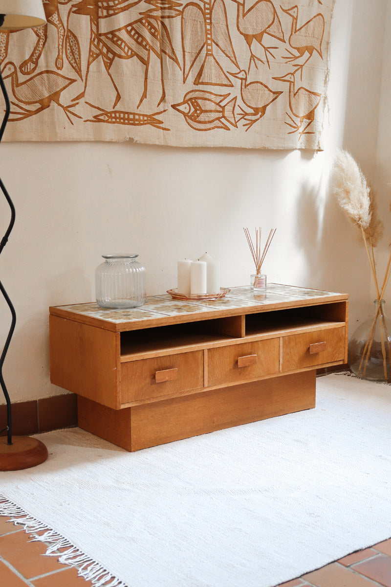 Meuble TV vintage en bois des années 70 avec plateau en céramique à motif floral, trois tiroirs et niches ouvertes.