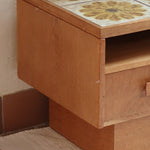 Meuble TV vintage en bois des années 70 avec plateau en céramique à motif floral, trois tiroirs et niches ouvertes.