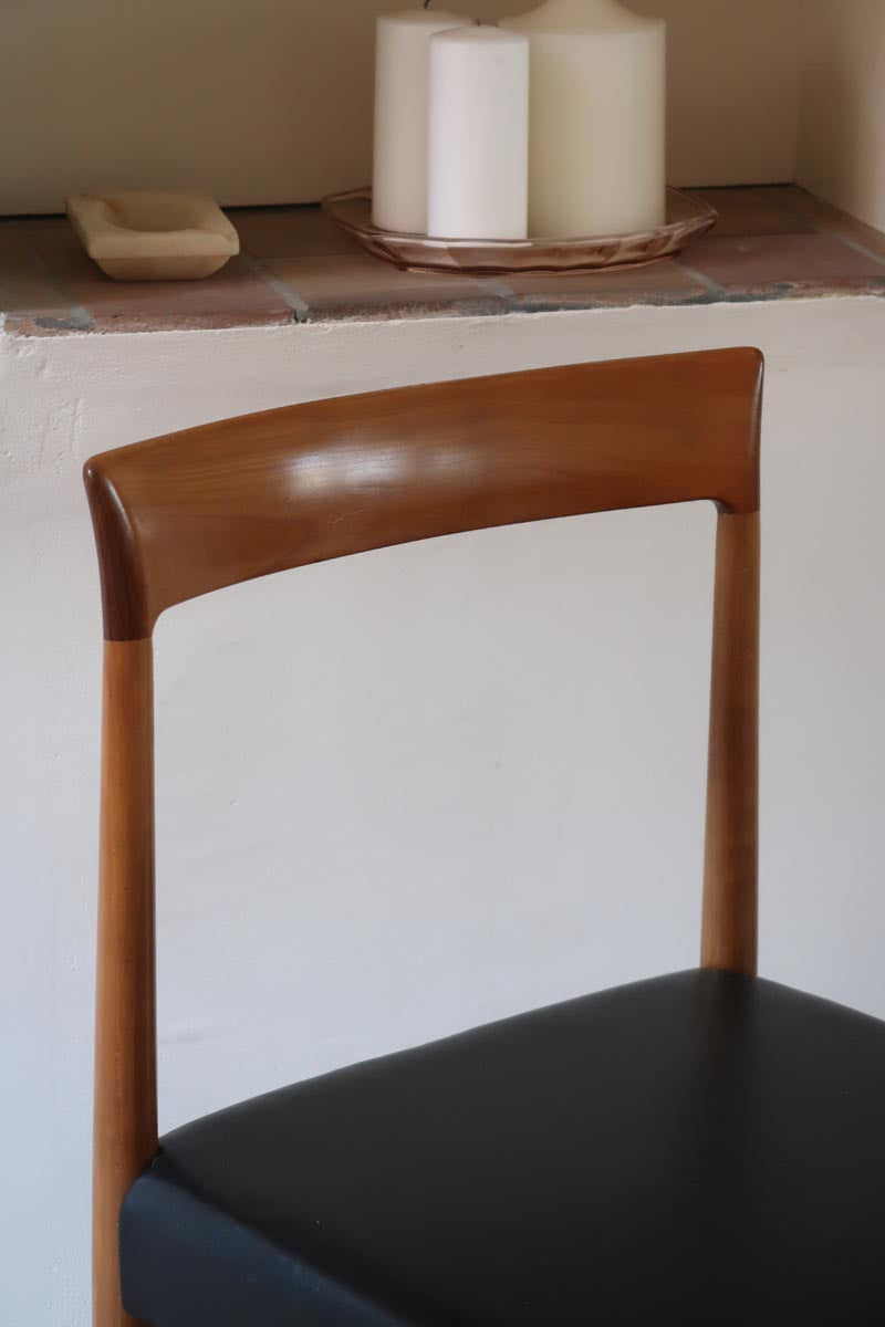 Paire de chaises scandinaves vintage en teck massif avec assise et dossier en skaï noir, design années 60, présentées seules et en mise en situation.