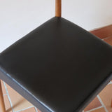 Paire de chaises scandinaves vintage en teck massif avec assise et dossier en skaï noir, design années 60, présentées seules et en mise en situation.