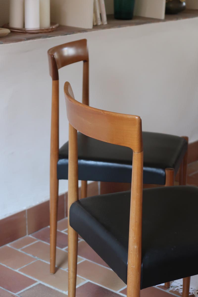 Paire de chaises scandinaves vintage en teck massif avec assise et dossier en skaï noir, design années 60, présentées seules et en mise en situation.