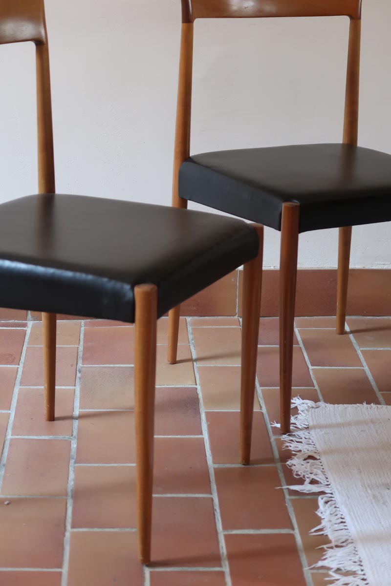 Paire de chaises scandinaves vintage en teck massif avec assise et dossier en skaï noir, design années 60, présentées seules et en mise en situation.