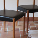 Paire de chaises scandinaves vintage en teck massif avec assise et dossier en skaï noir, design années 60, présentées seules et en mise en situation.