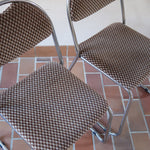 Paire de chaises vintage en chrome tubulaire avec assise et dossier en tissu à motif géométrique.
