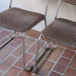 Paire de chaises vintage en chrome tubulaire avec assise et dossier en tissu à motif géométrique.
