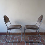 Paire de chaises vintage en chrome tubulaire avec assise et dossier en tissu à motif géométrique.
