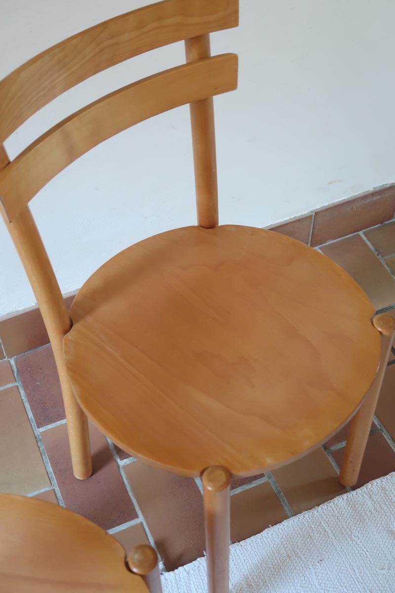Paire de chaises vintage en hêtre massif, assise ronde et dossier à deux barreaux, style bistrot scandinave, présentées seules et en mise en situation.
