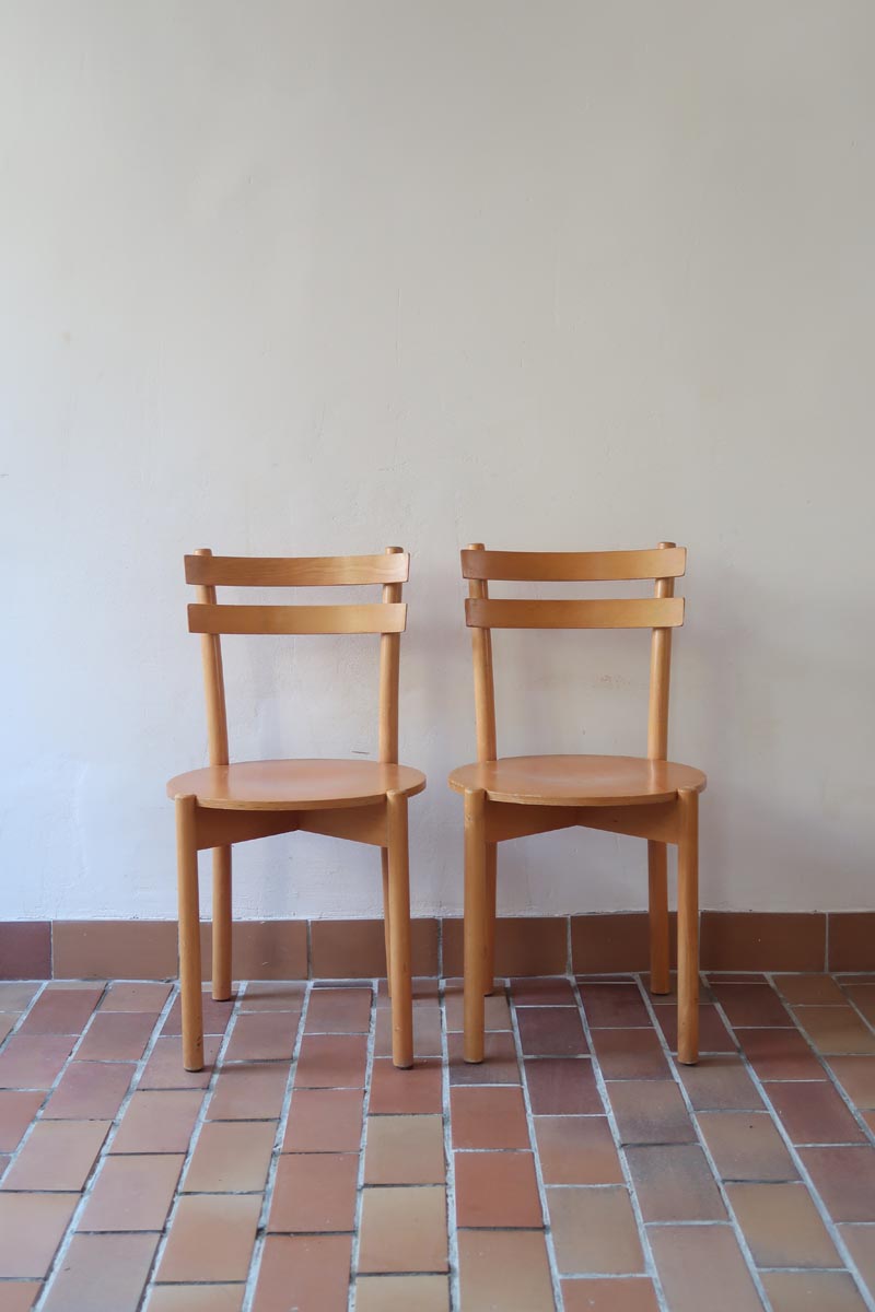 Paire de chaises vintage en hêtre massif, assise ronde et dossier à deux barreaux, style bistrot scandinave, présentées seules et en mise en situation.