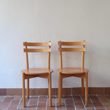 Paire de chaises vintage en hêtre massif, assise ronde et dossier à deux barreaux, style bistrot scandinave, présentées seules et en mise en situation.