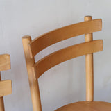 Paire de chaises vintage en hêtre massif, assise ronde et dossier à deux barreaux, style bistrot scandinave, présentées seules et en mise en situation.