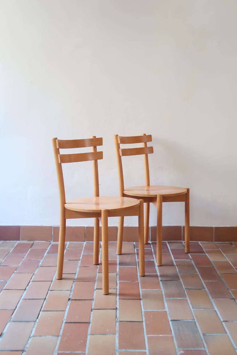 Paire de chaises vintage en hêtre massif, assise ronde et dossier à deux barreaux, style bistrot scandinave, présentées seules et en mise en situation.