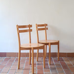 Paire de chaises vintage en hêtre massif, assise ronde et dossier à deux barreaux, style bistrot scandinave, présentées seules et en mise en situation.