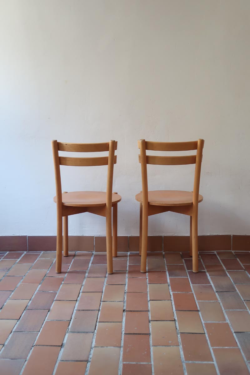 Paire de chaises vintage en hêtre massif, assise ronde et dossier à deux barreaux, style bistrot scandinave, présentées seules et en mise en situation.