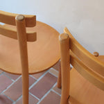 Paire de chaises vintage en hêtre massif, assise ronde et dossier à deux barreaux, style bistrot scandinave, présentées seules et en mise en situation.